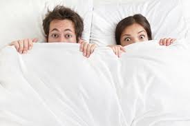 man and woman in bed just eyes poking out